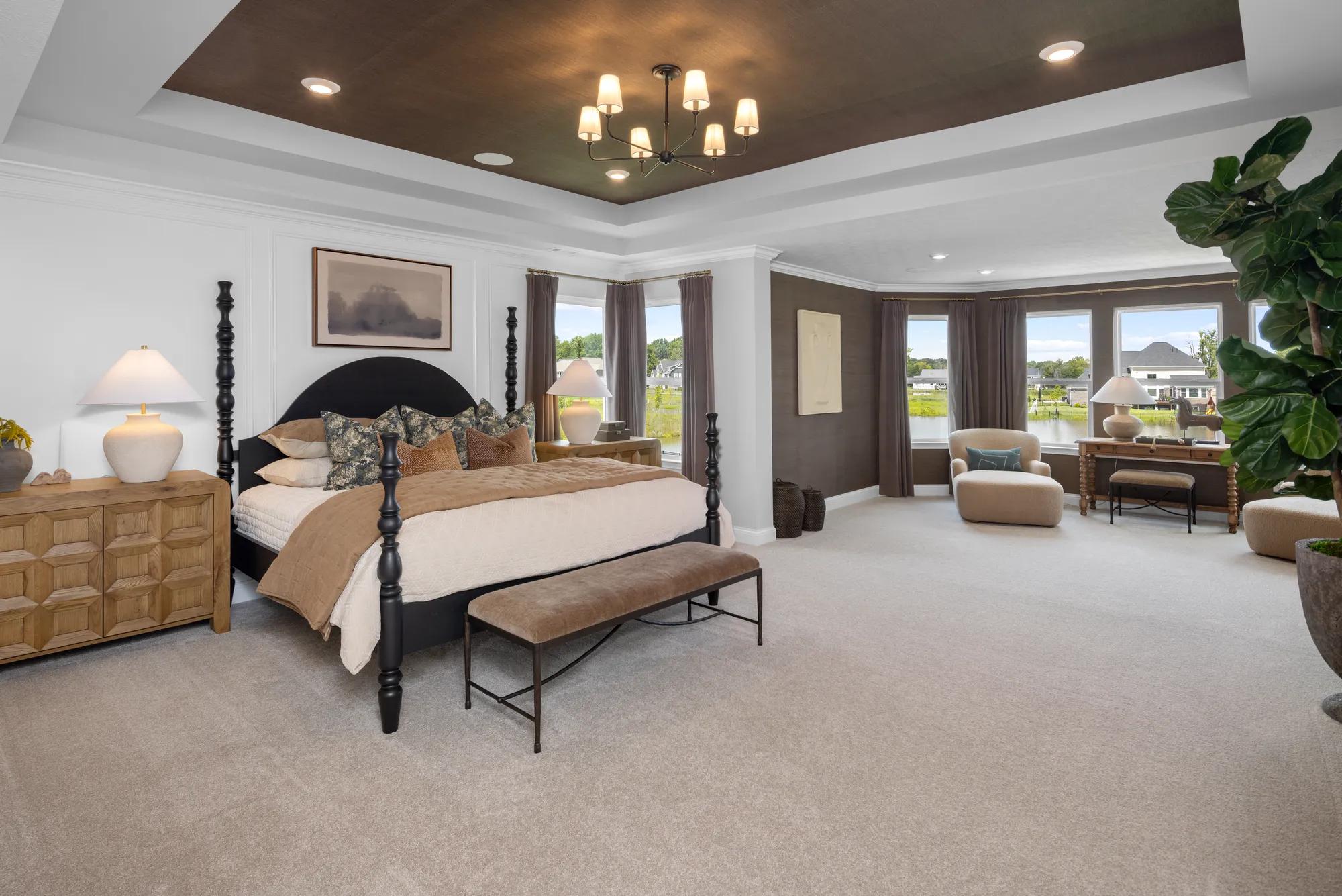 Sophisticated new home primary bedroom with accent ceiling and spacious sitting room