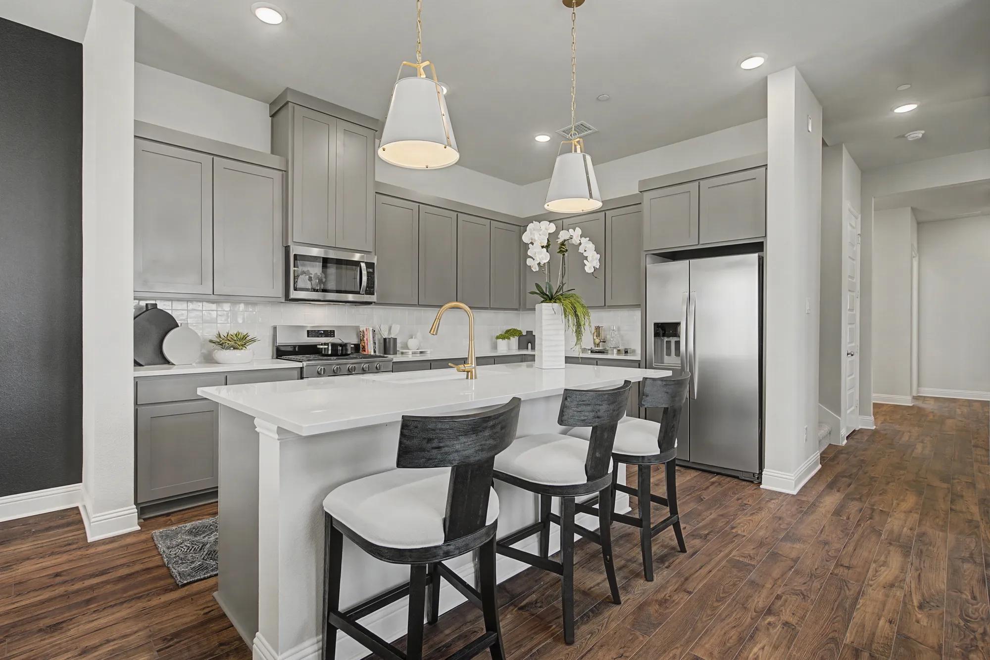 New townhome kitchen with gray cabinets, white tile backsplash, and white countertops